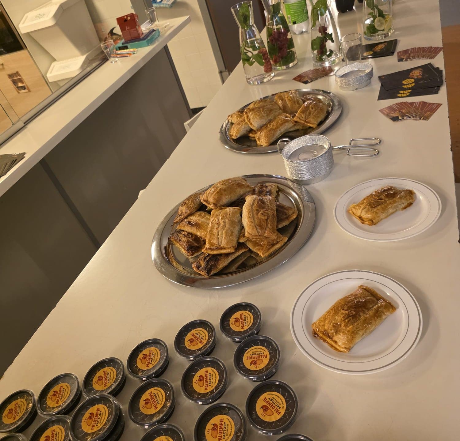 Een proeverij klaargezet op een bar: schalen met Paloempies, borden en een rij sauspotjes met het logo erop